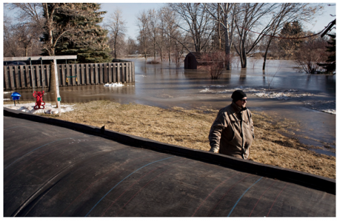 The big black thing in the foreground is part of a water-filled dyke that was deployed against the flooding of the Red River in North Dakota. Image Source: (MPR Photo/Ann Arbor Miller)
