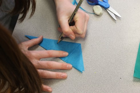 Drawing a pattern on folded paper.