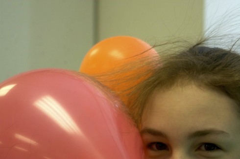 Hair attracted to a balloon by static electrical forces.