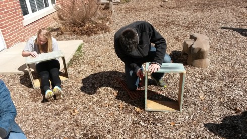 Students use sandpaper to prepare the outsides of donated hives for painting.