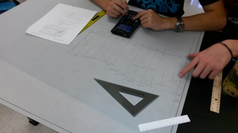 Students drawing trapezoids to fit the outline of the guitar, and calculating their areas.